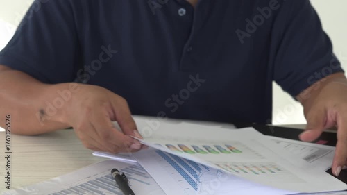 Focused young asian man reading and checking paper documents, signing the contract to send to her business partner. Concentrated smart ambitious businessman is organizing the paper works.
