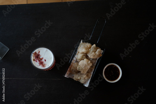 Delicious fried snacks with dipping sauce and creamy drink on dark table, perfect for restaurant menus or food blogs promoting tasty treats