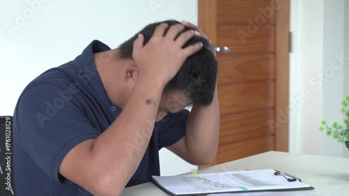 An asian businessman is suffering from headache, tension from forehead and getting stress and depression during working, massaging his head, employee life office stress and office syndrome concept.