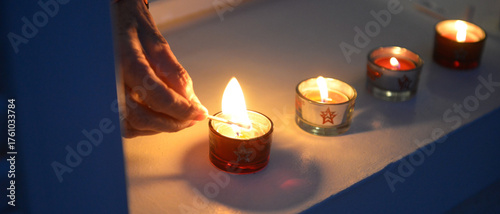 Tableau sur toile Détail sur la main d'une femme senior qui allume plusieurs petites bougies sur l