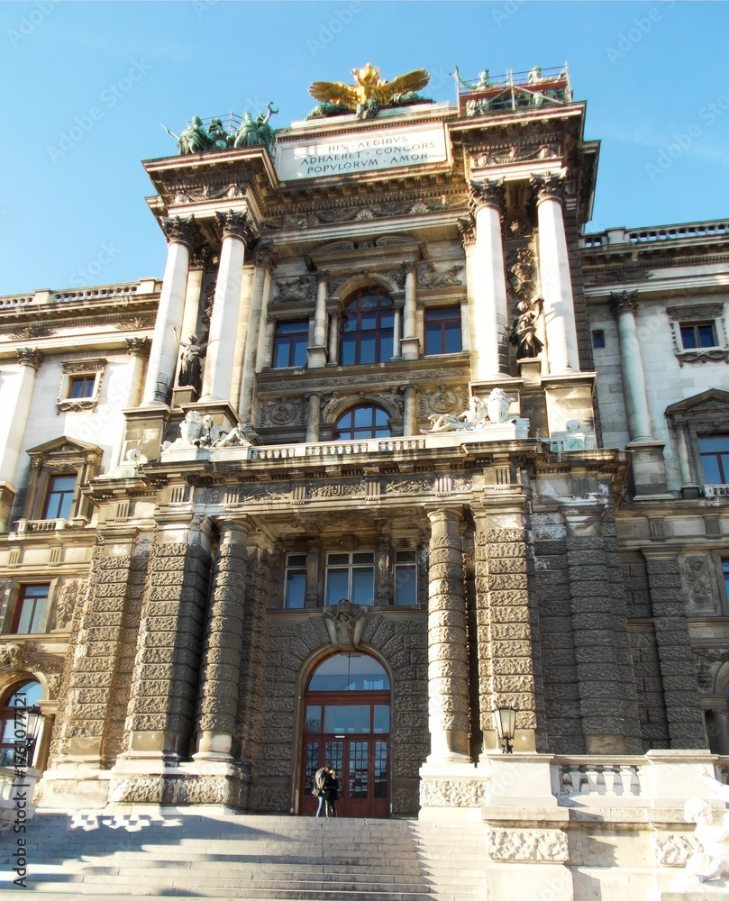Obraz premium Hofburg New Wing Vienna, massive imperial entrance with ornate relief, column pairs, historic sculptures and golden eagle crest in sunlight