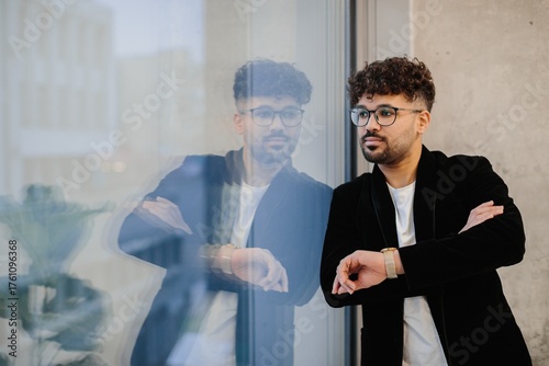 Fotografie Young man checking watch reflecting on business future