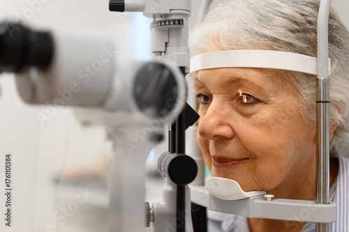 Vászonkép Close-up of mature woman undergoing eye examination with slit lamp for vision ch