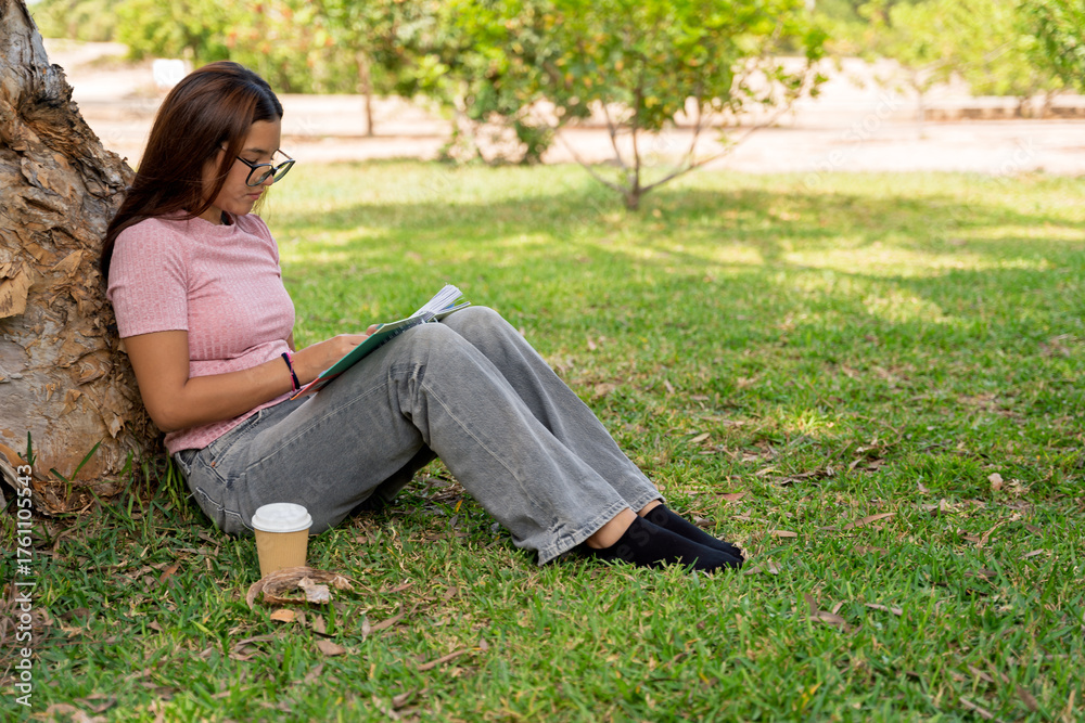 Obraz premium Teenage girl studying notes under a park tree