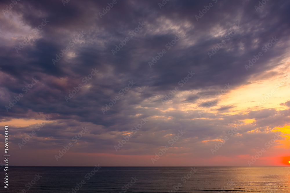 Naklejka premium dramatic sky at sunrise at the sea. wonderful atmospheric background for wallpaper. stormy clouds above the water. sun over horizon. nature landscape of sozopol bay in summer. warm colorful gradient