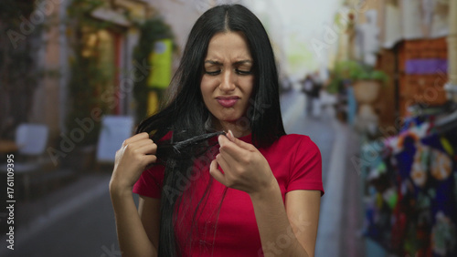 Woman expressing displeasure with long hair on a vibrant city street, showcasing a young hispanic female outdoors in an urban environment during a sunny day.