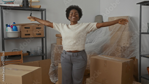 Young woman rejoicing in modern living room surrounded by unpacked boxes denotes new beginning and excitement within her urban apartment environment.