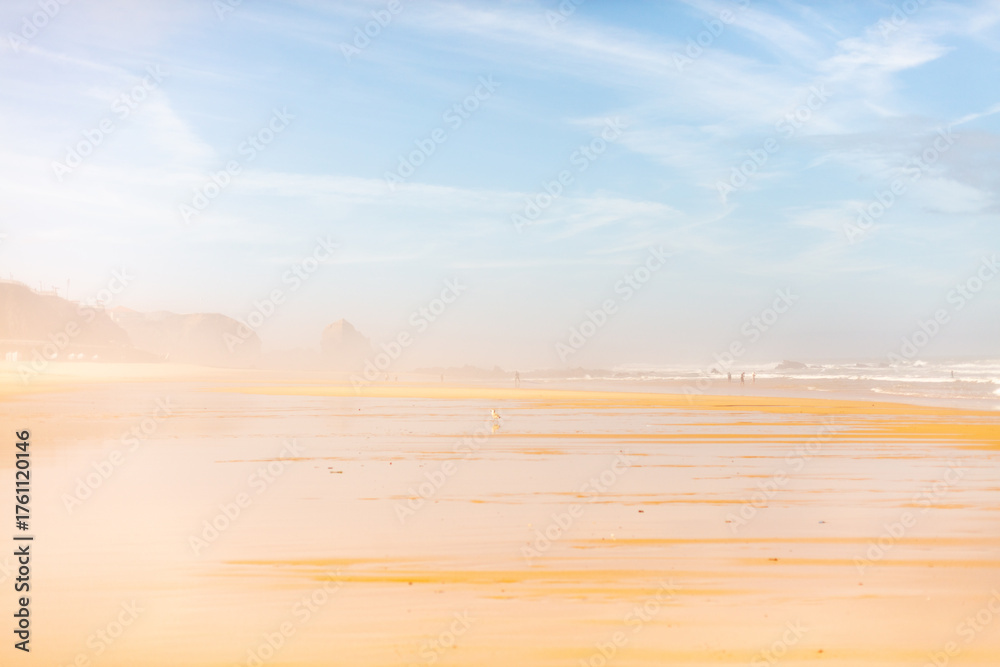 Fototapeta premium Santa Cruz, Torres Vedras, Portugal. 10 September 2025. Wide sandy beach with ocean waves under clear blue sky.