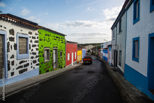 Fototapeta Naklejka Na Ścianę i Meble -  Colorful traditional houses on a narrow street in a small village in the Canary Islands, with a car driving downhill.