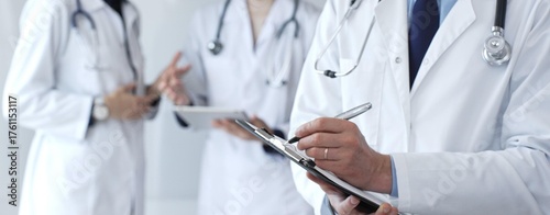 Fotografie Doctor writing on a clipboard during a medical team discussion, collaborating on