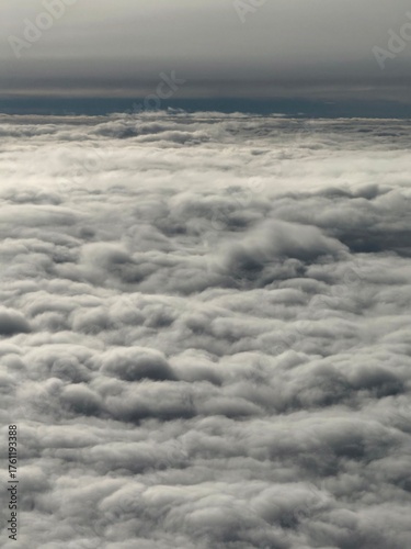 Close-up view of fluffy white clouds from airplane altitude. Beautiful aerial landscape with soft textures and bright daylight atmosphere