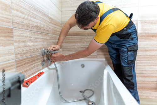 Quadro su tela Plumber installing new fixtures in a bathroom tub during daytime work hours