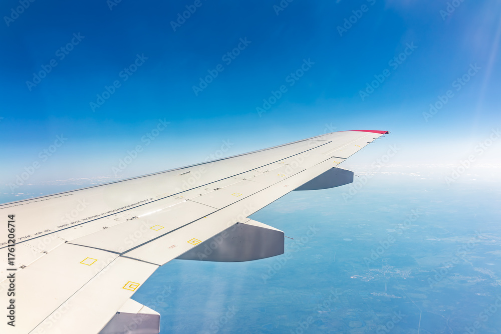 Fototapeta premium View from the airplane window at a beautiful blue clear sky and the airplane wing