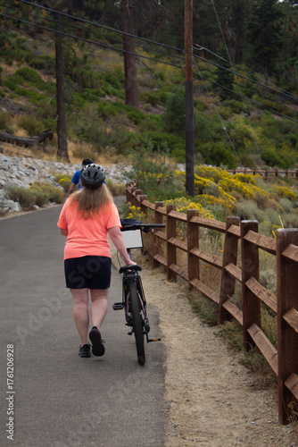 MUJER EN SENDERO CAMINANDO JUNTO A BICICLETA DE CICLISMO