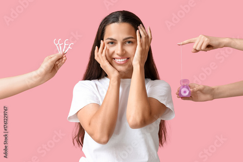 Beautiful young woman and female hands with dental floss on pink background