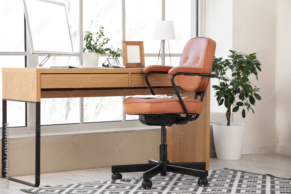 Fototapeta premium Brown leather swivel chair and workplace with modern computer near window in office