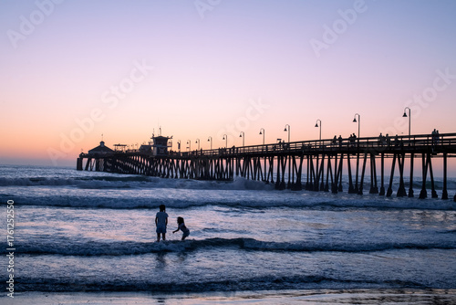Two kids silhouetted and playing at sunset at the Imperial beach pier with lovely purple hues