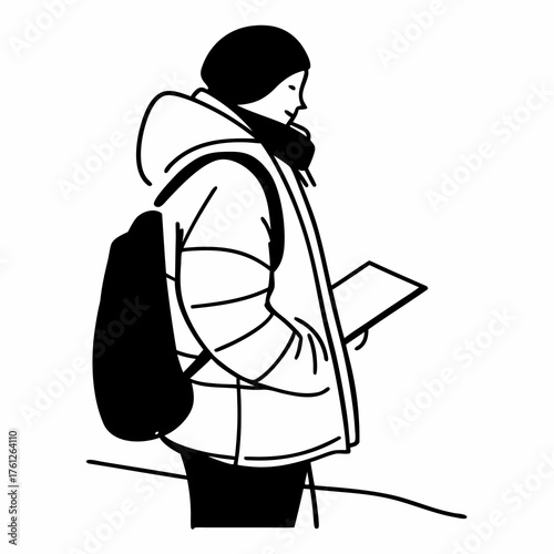 Young woman reading a book while standing outdoors in winter  