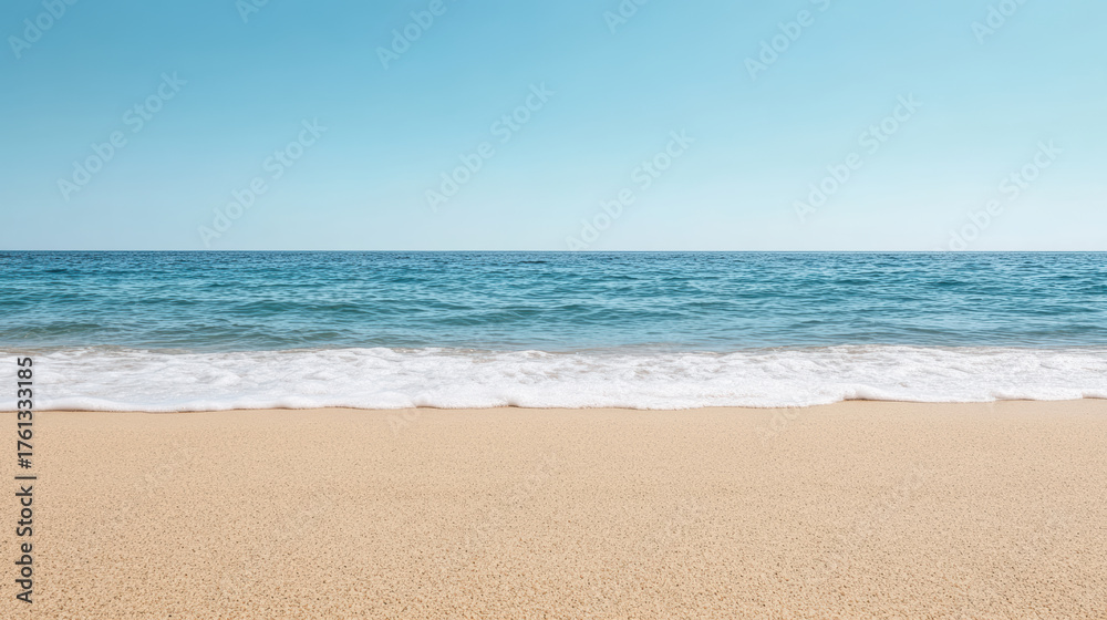 Obraz premium Calm beach scene with soft horizon, clear blue sky, and gentle waves lapping at shore