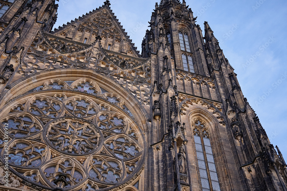 Fototapeta premium Detailed Gothic facade of St Vitus Cathedral with rose window and spires under blue sky in Prague, Czech Republic. Concept of religion, heritage and medieval architecture