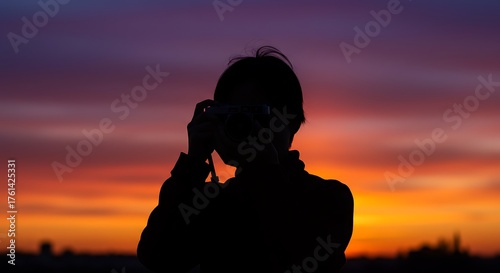 Silhouette of a person taking a photo during sunset.