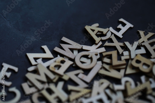 Scattered Wooden Alphabet Letters on Dark Cracked Surface for Creative Design and Typography