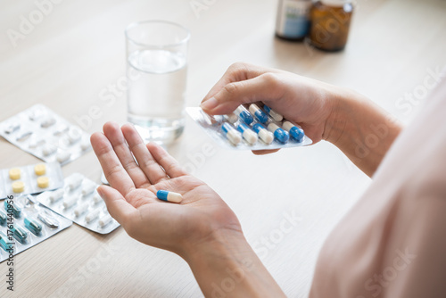 Bild auf Leinwand Sick ill asian young woman, girl hand taking tablet pill capsule out from blister pack, painkiller medicine from stomach pain, head ache, pain for treatment, take drug or vitamin at home, health care