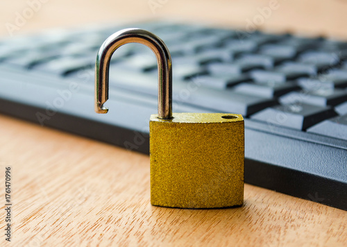 A small golden padlock standing open on a computer keyboard symbolizing cybersecurity breach, data protection risk or online account vulnerability.