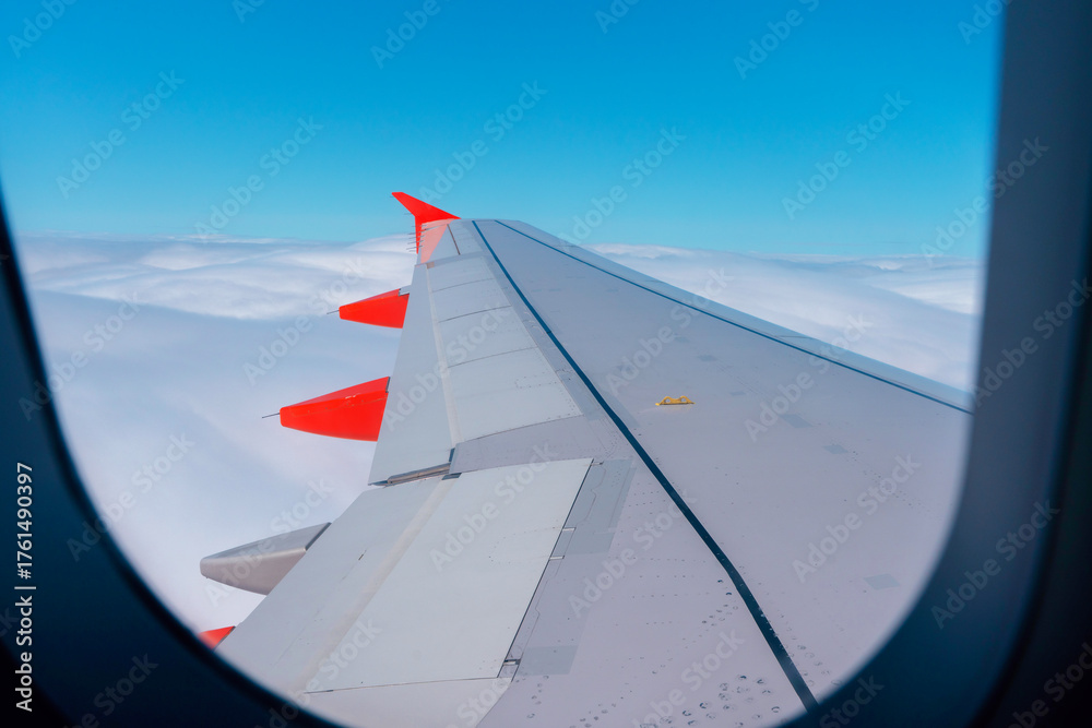 Obraz premium View of an airplane wing above fluffy clouds during a bright daytime flight