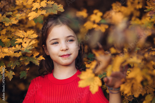 Girl in autumn nature, standing among autumn leaves.