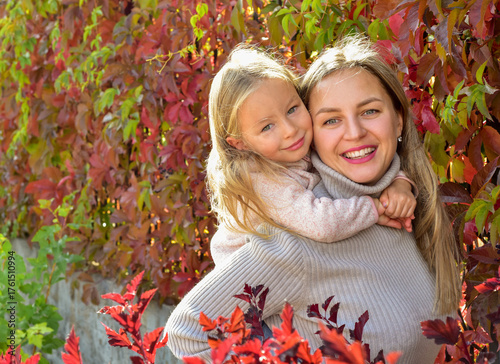 Mother and daughter on a walk. Autumn season. Bright autumn leaves. Sunny day. Happy family outdoors