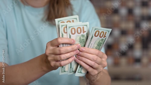 Female hands carefully counting one-hundred-dollar bills, calculating family budget expenses, saving money for high utility bills, or making a large cash payment for services