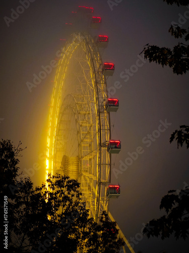 Moscow, Russia - October 19, 2025: The Moscow Sun Ferris wheel in thick fog with night illumination at VDNKh Park.