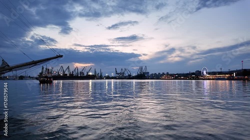 Industrial seaport skyline with cargo cranes silhouetted at sunset. Panoramic view of a commercial harbor, representing global trade, shipping, and logistics.