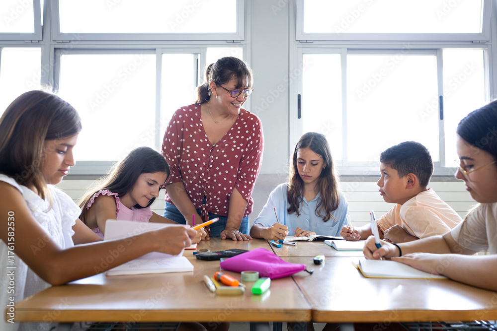 Fototapeta premium Teacher helping elementary school students studying in classroom