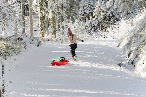 Child Pulling Sled in Snowy Forest