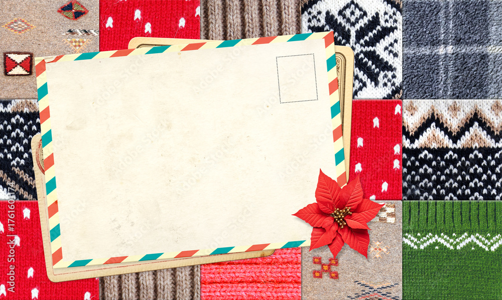 Fototapeta premium Letter to Santa Claus. Christmas background with retro postcard and poinsettia on wool sweater texture. Nostalgic holiday backdrop with cozy knitted wool material and vintage card. Copy space for text