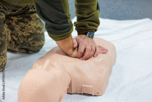Fényképezés First aid training for soldiers performing CPR chest compressions on a medical d