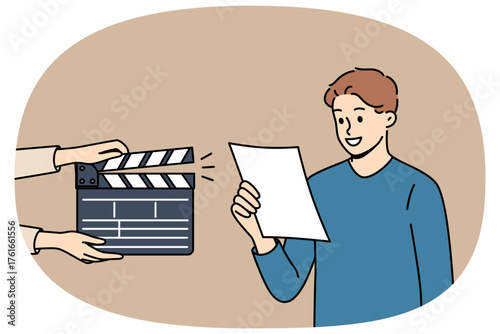 Man actor participates in casting, reading text from piece of paper, standing near clapperboard. Guy participates in casting and starred in popular tv series or movies to become famous star.