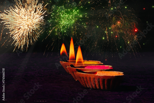 Happy Diwali Celebration concept , 3 Diyas in foreground and fireworks in background 
