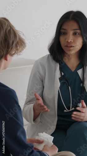Female doctor shows empathy and explains medical advice to a distressed teenage boy in a hospital consultation, offering support and calm during an emotional visit