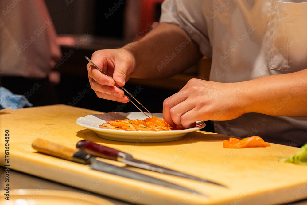 Obraz premium Chef preparing sushi with precision using chopsticks in a vibrant kitchen