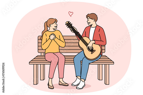 Man sings romantic serenade to woman and plays guitar, sitting on bench during date in park. Romantic couple located on street and sings songs, enjoying communication and having love attraction