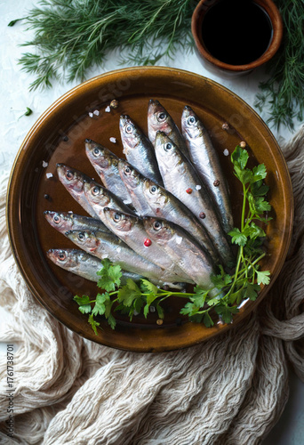 Freshly caught sardines arranged on a rustic wooden platter with herbs
