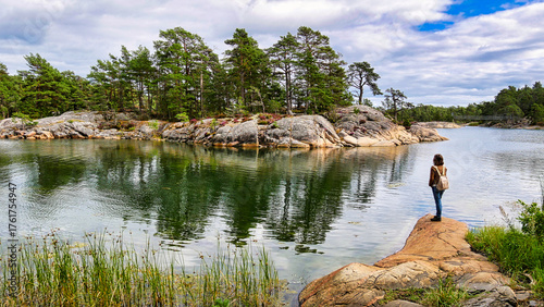 Wanderin beobachtet auf einer Felskuppe die gegenüberliegende Schäreninsel im Naturreservat Stendörren in Schweden