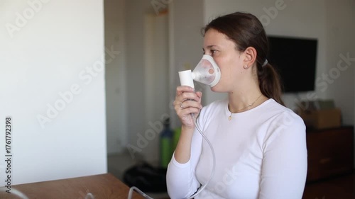 Young woman using a nebulizer mask to manage breathing