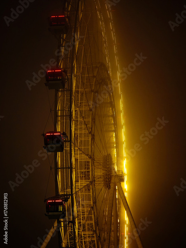 The Moscow Sun Ferris wheel in thick fog with night illumination at VDNKh Park.