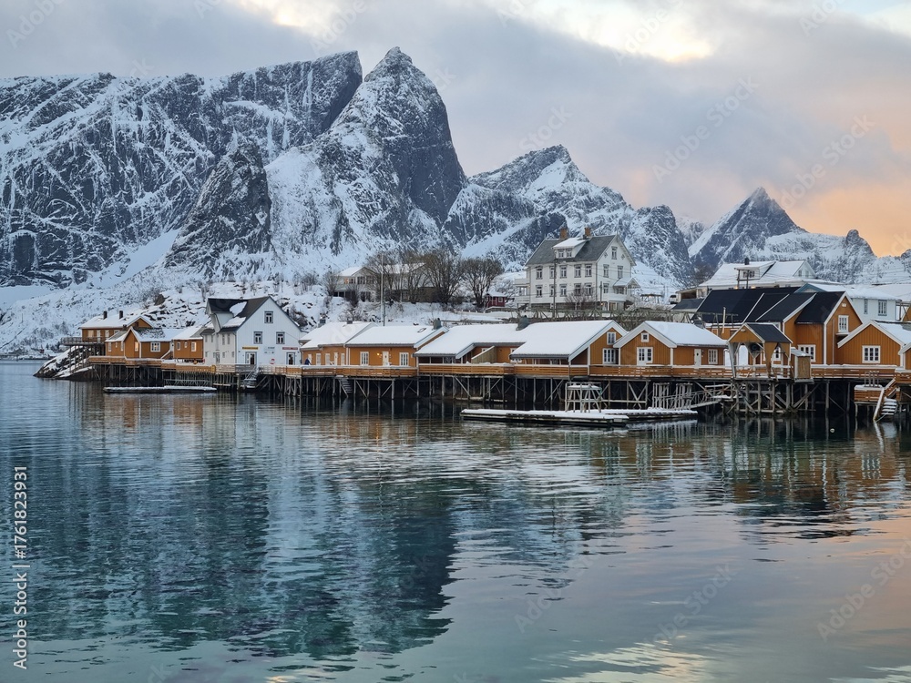 Fototapeta premium Beautiful view of scenic Lofoten Islands archipelago winter scenery with traditional yellow fisherman Rorbuer cabins in the historic village of Sakrisoy at sunrise, Norway, Scandinavia 