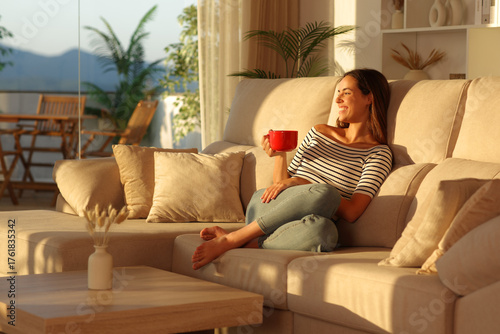 Happy woman drinking coffee from red cup in a house