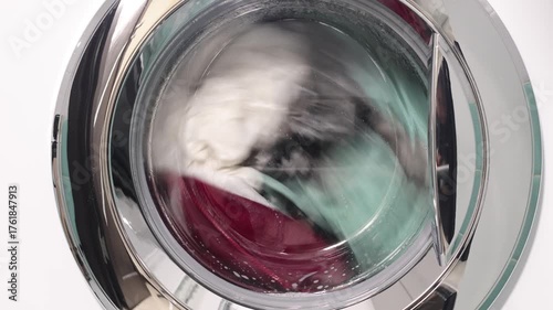 Laundry spinning and washing inside a washing machine, close-up of clothes in motion during wash cycle.